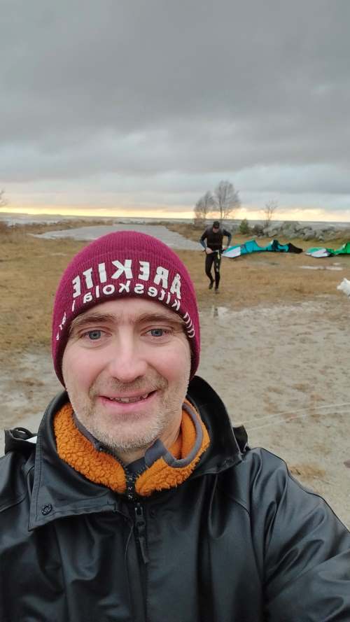 Jonas Hölund in front of the sea and kiters and kiters in the background